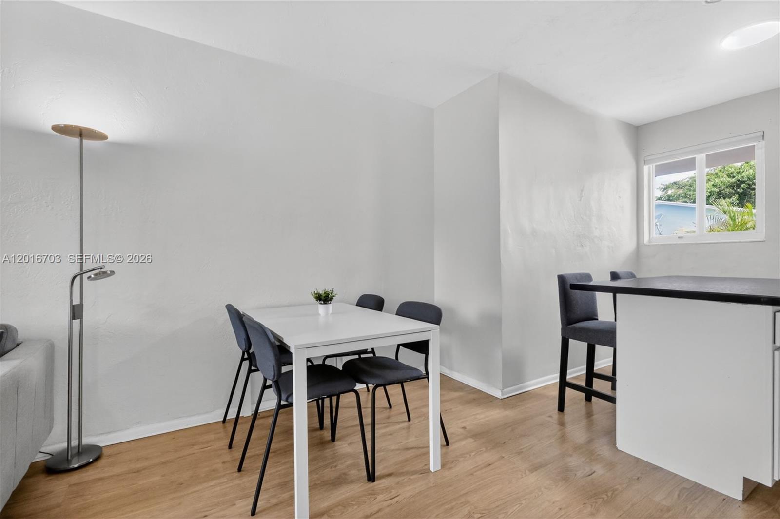 A dining area features a white table with four chairs and a nearby floor lamp — 1003 NE 110th St # 1003, Biscayne Park FL 33161, BISCAYNE PARK, FL