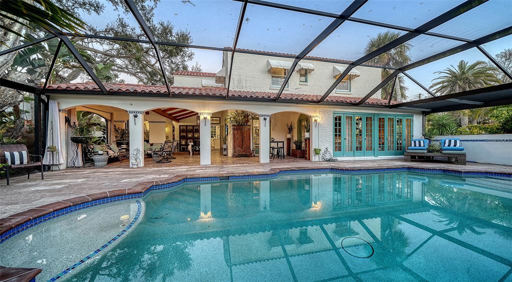 A swimming pool with a spa sits under a screened enclosure beside a covered patio — 547 N SHORE DRIVE, SARASOTA, FL