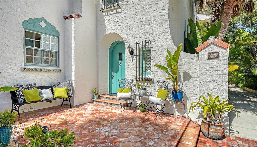 A white stucco house features a turquoise arched front door and a terracotta tiled patio — 547 N SHORE DRIVE, SARASOTA, FL