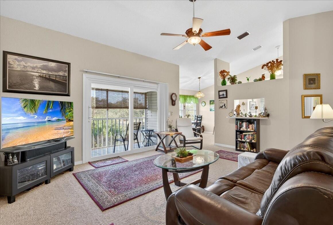 A living room features a brown leather sofa, a glass coffee table, and a sliding door — 1810 Waterford Drive # 6, Vero Beach FL 32966, VERO BEACH, FL