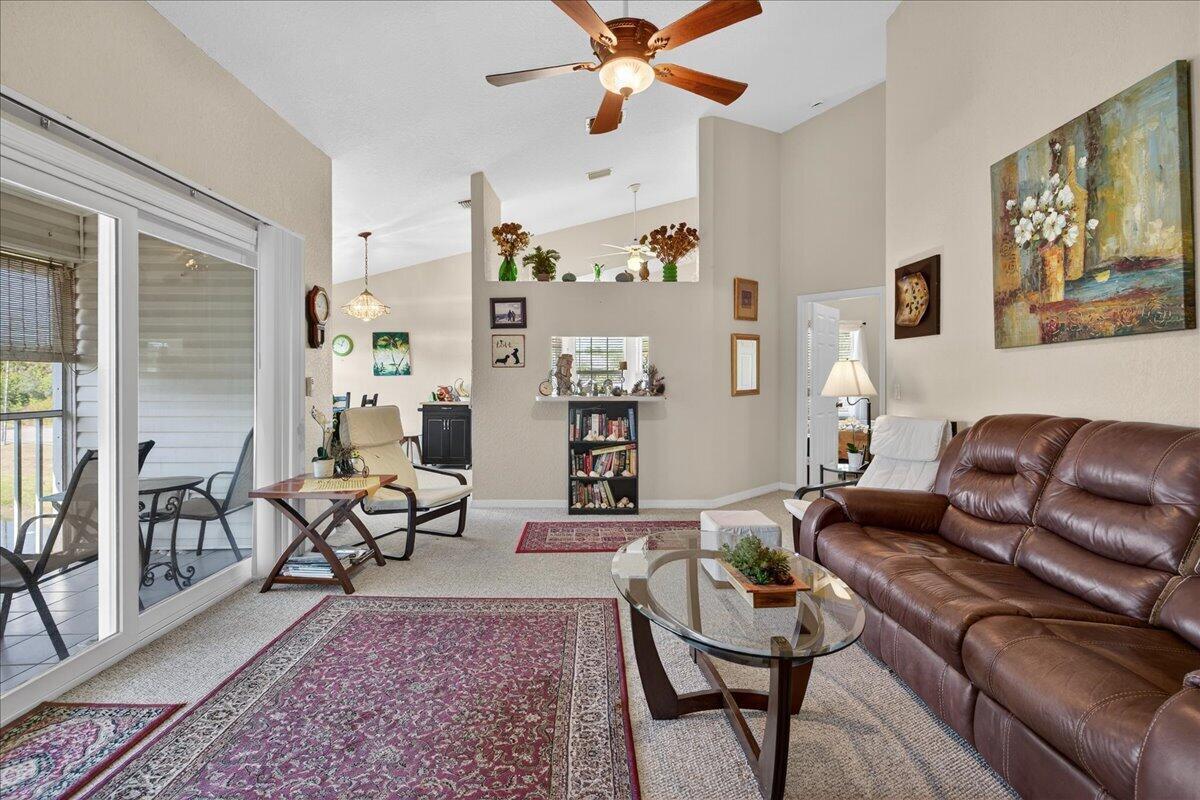 A living room features a brown leather sofa, a glass coffee table, and vaulted ceilings — 1810 Waterford Drive # 6, Vero Beach FL 32966, VERO BEACH, FL