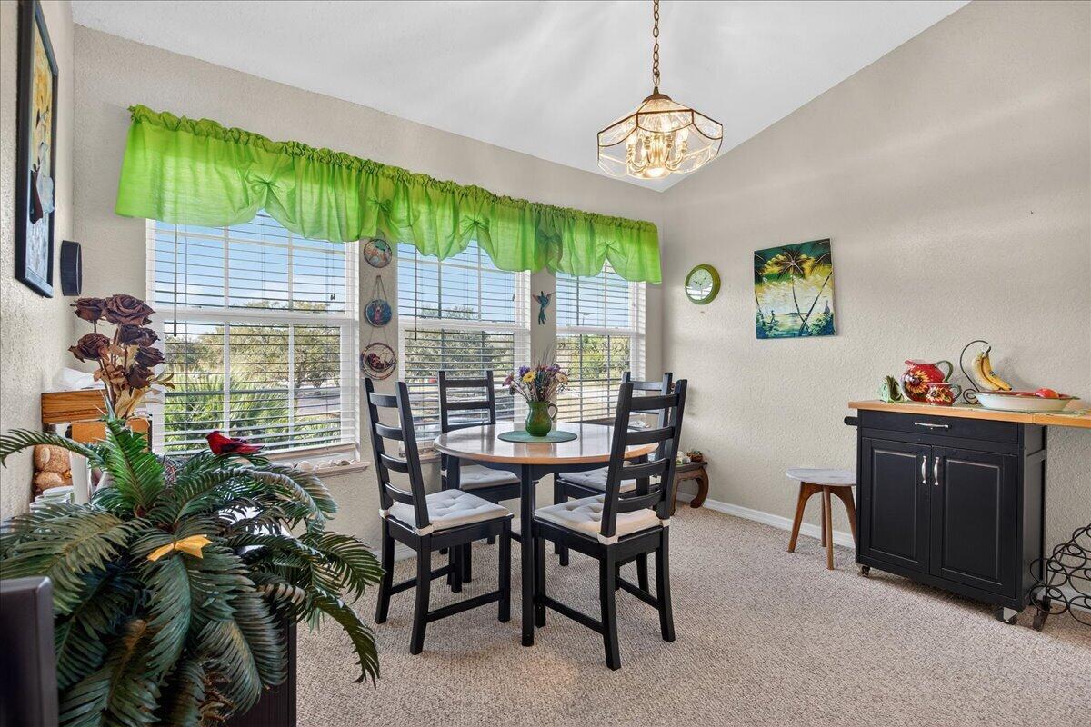 A dining area with a round table, four chairs, a black cabinet, and large windows — 1810 Waterford Drive # 6, Vero Beach FL 32966, VERO BEACH, FL