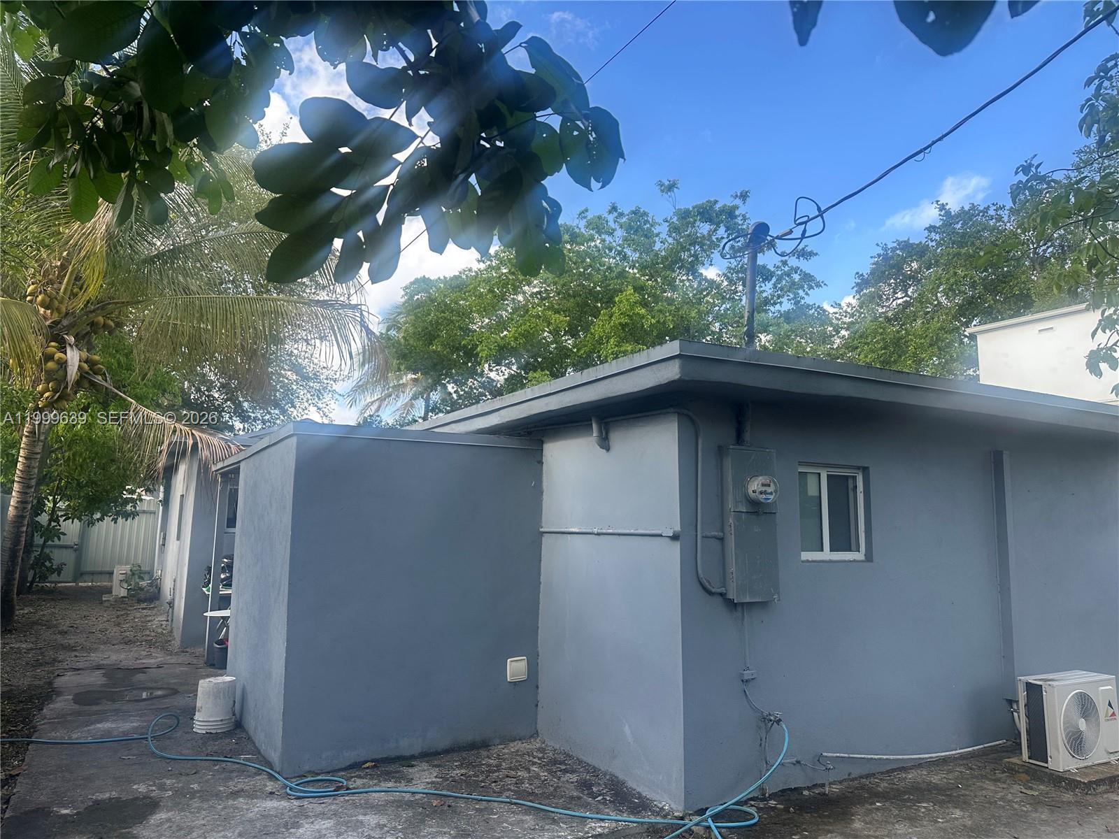 The exterior of a gray, flat-roofed house features an electrical meter and an air conditioner — 1790 NW 112th St, Miami FL 33167, MIAMI, FL