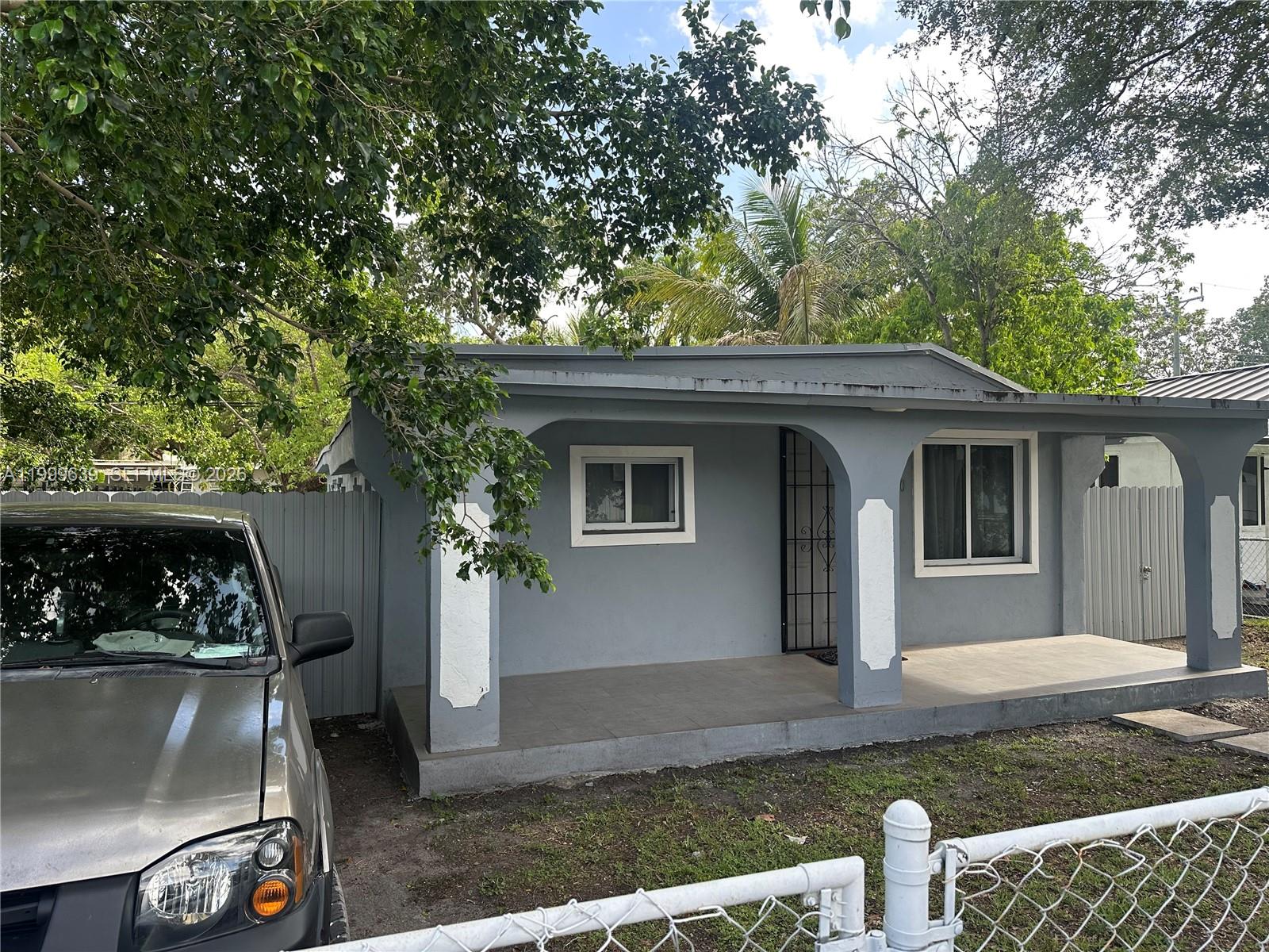 A gray single-story house features a covered front porch with arched columns and a driveway — 1790 NW 112th St, Miami FL 33167, MIAMI, FL