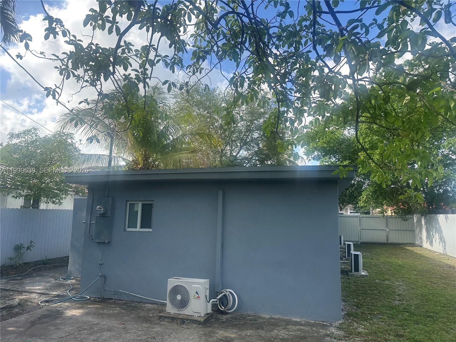 The exterior of a gray concrete building features a small window and an air conditioning unit — 1790 NW 112th St, Miami FL 33167, MIAMI, FL