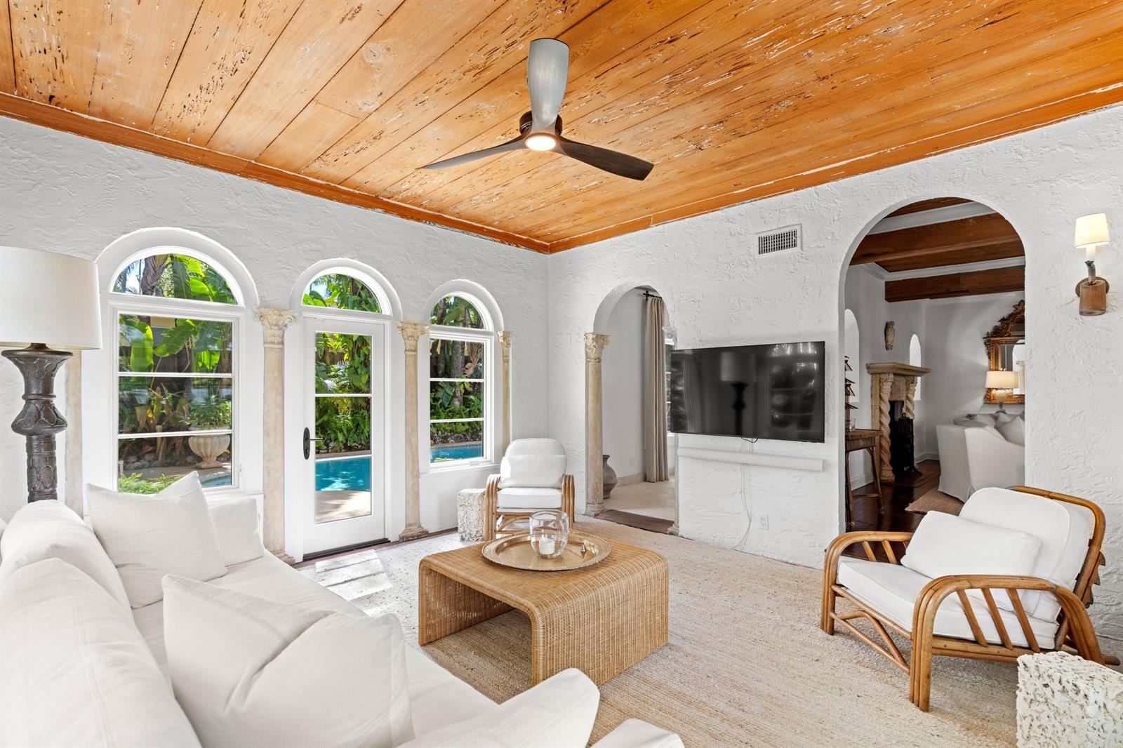 A sunlit living room features a wood-plank ceiling, white textured walls, and arched glass doors — 746 Upland Road, West Palm Beach FL 33401, WEST PALM BEACH, FL
