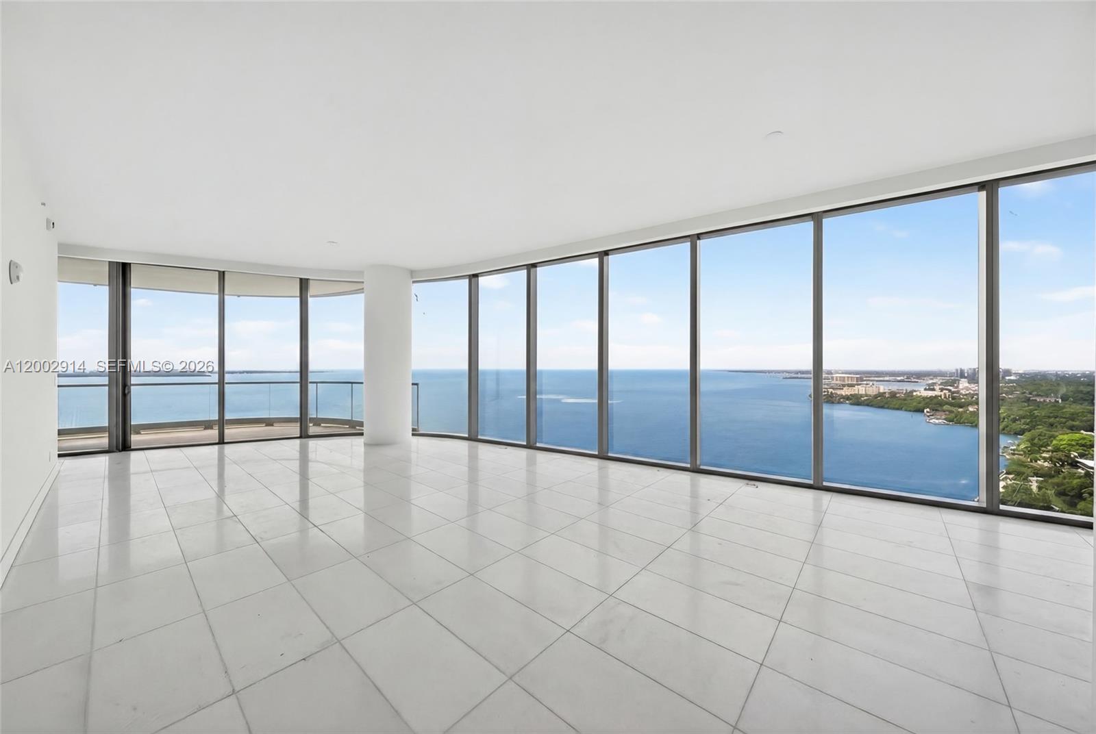 An empty room with white tile floors and floor-to-ceiling windows overlooking the ocean — 175 SE 25 Rd # 2602, Miami FL 33129, MIAMI, FL