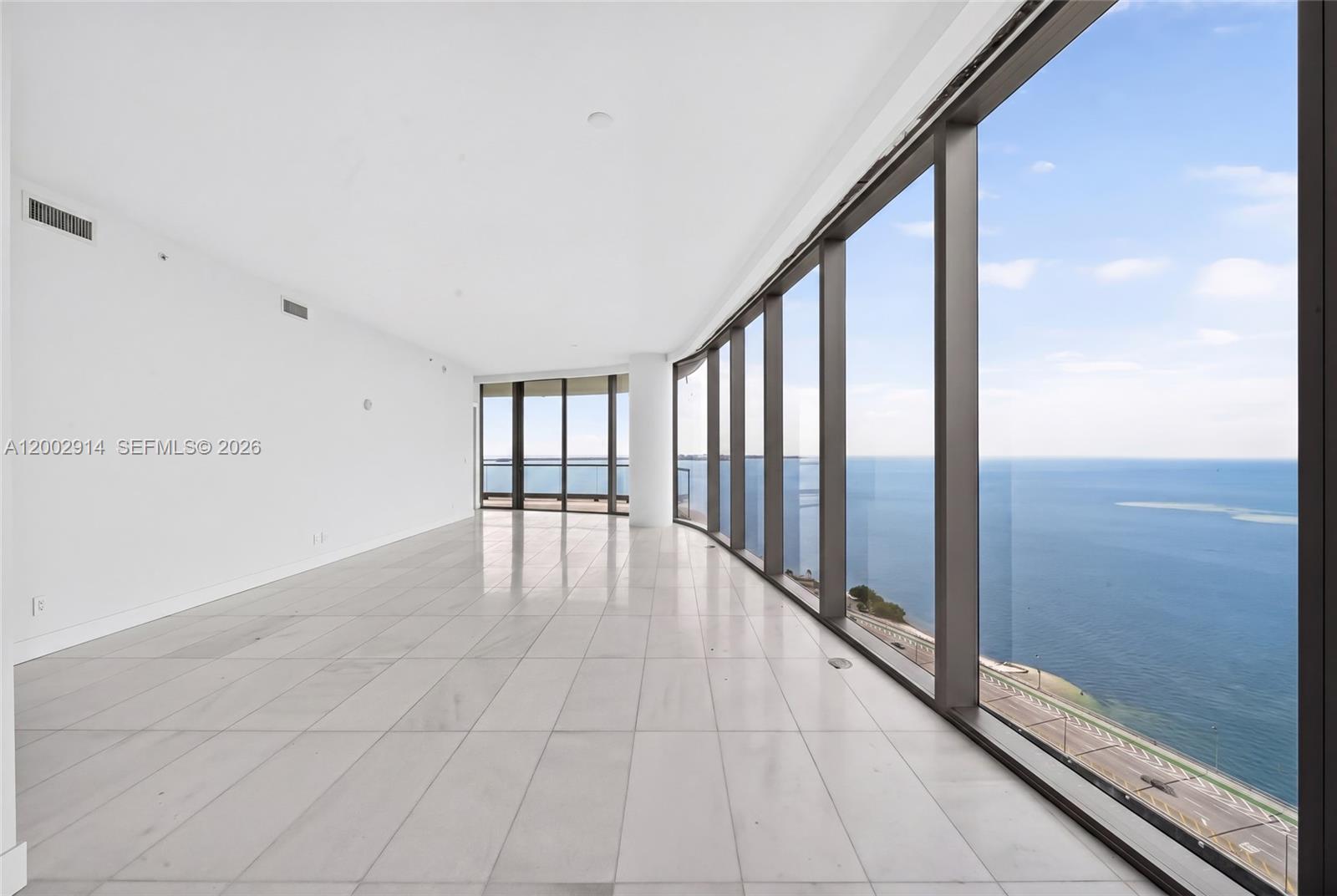 An empty room with white tile floors and floor-to-ceiling windows overlooking the ocean — 175 SE 25 Rd # 2602, Miami FL 33129, MIAMI, FL