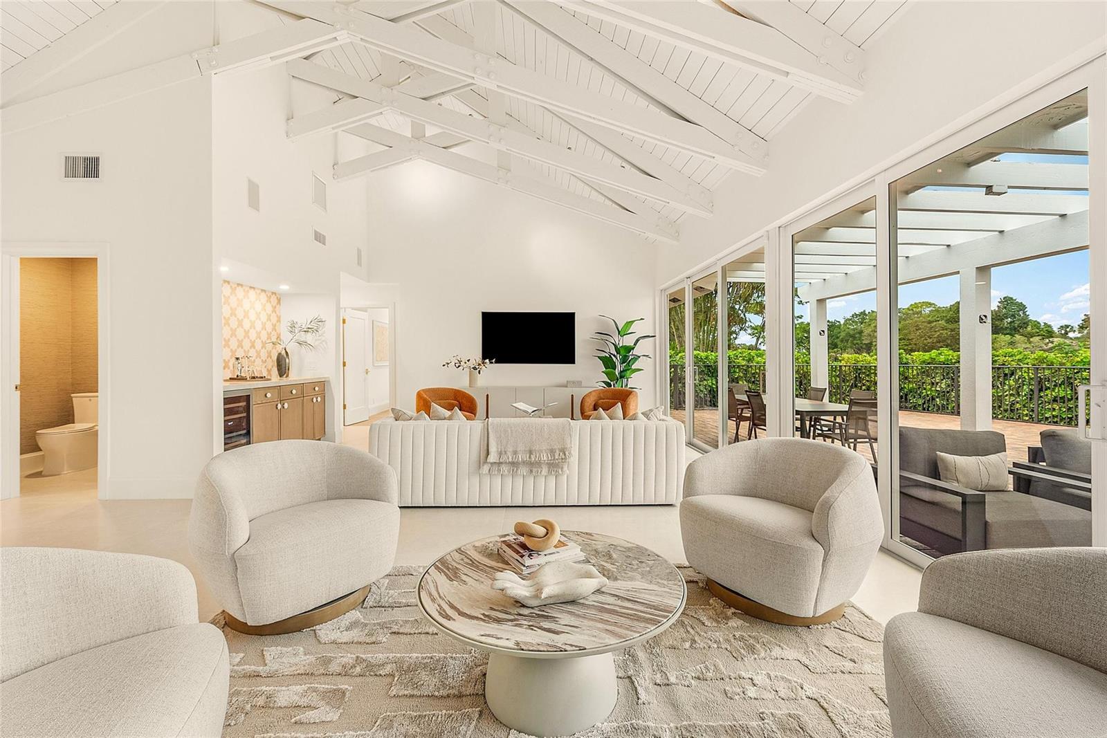 A bright living room features a vaulted ceiling, white furniture, and large glass sliding doors — 4877 Pineview Circle, Delray Beach FL 33445, DELRAY BEACH, FL