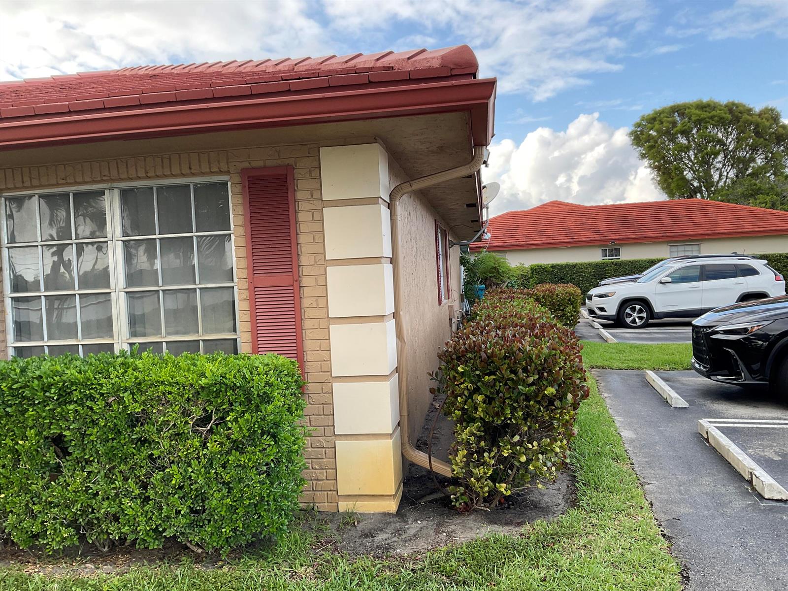 The exterior of a brick building features a red tile roof and a corner column — 1473 SW 27th Avenue # 1e, Boynton Beach FL 33426, BOYNTON BEACH, FL