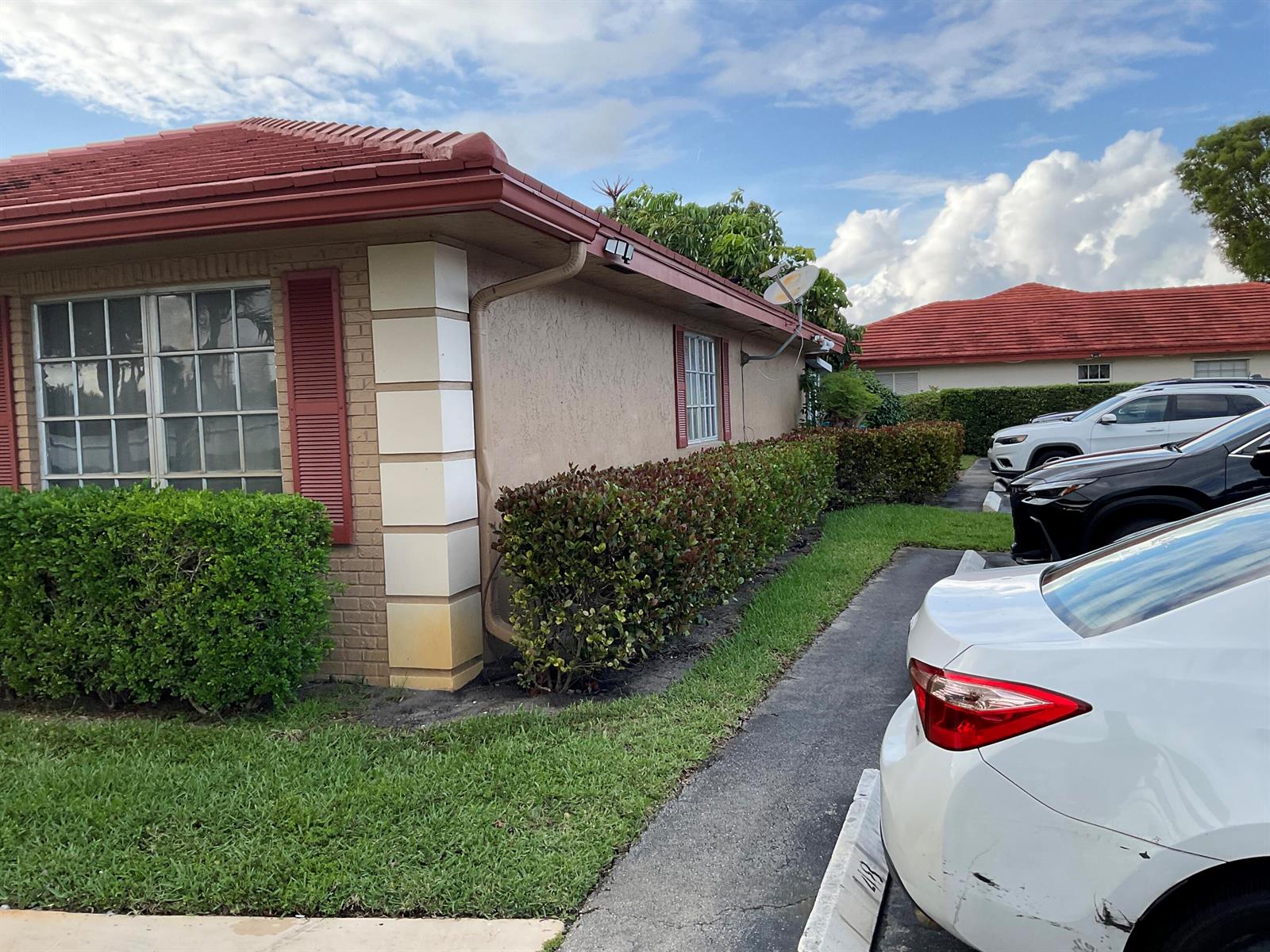 A single-story house with a tiled roof, brick accents, and a row of hedges — 1473 SW 27th Avenue # 1e, Boynton Beach FL 33426, BOYNTON BEACH, FL