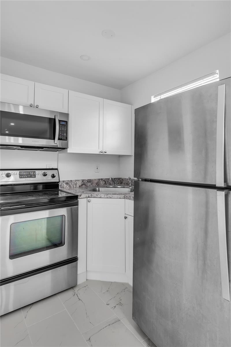 A kitchen features white cabinets, stainless steel appliances, and gray marble-patterned countertops — 6950 NW 8th Ave # 3, Miami FL 33150, MIAMI, FL