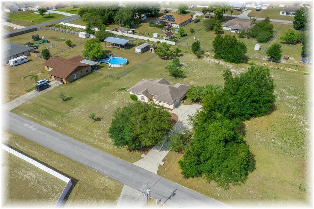 An aerial view shows a single-story house with a driveway and trees on a lot — 8740 SE 61 AVENUE, OCALA, FL
