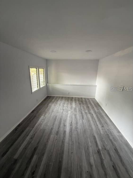 An empty room features light gray walls, wood-look vinyl flooring, and two windows — 5500 N ROME AVENUE UNIT 29, TAMPA, FL