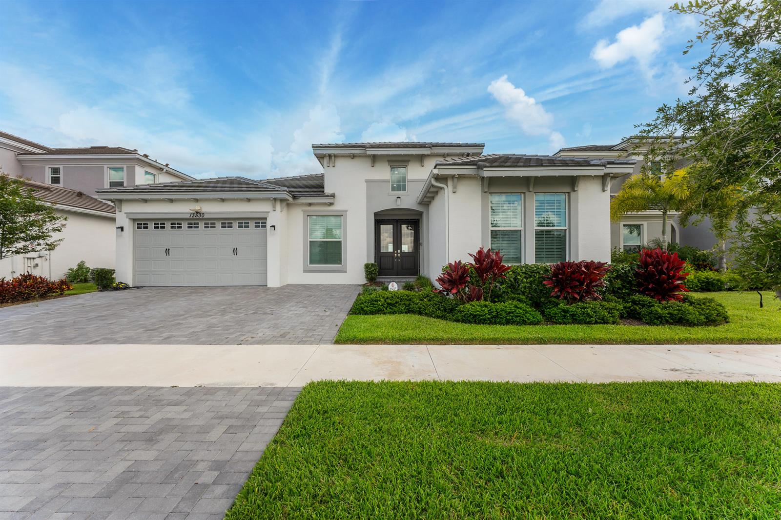 A single-story house with a gray garage, dark front doors, and landscaped front yard — 13530 Spruce Pine Drive, FL 33470, FL