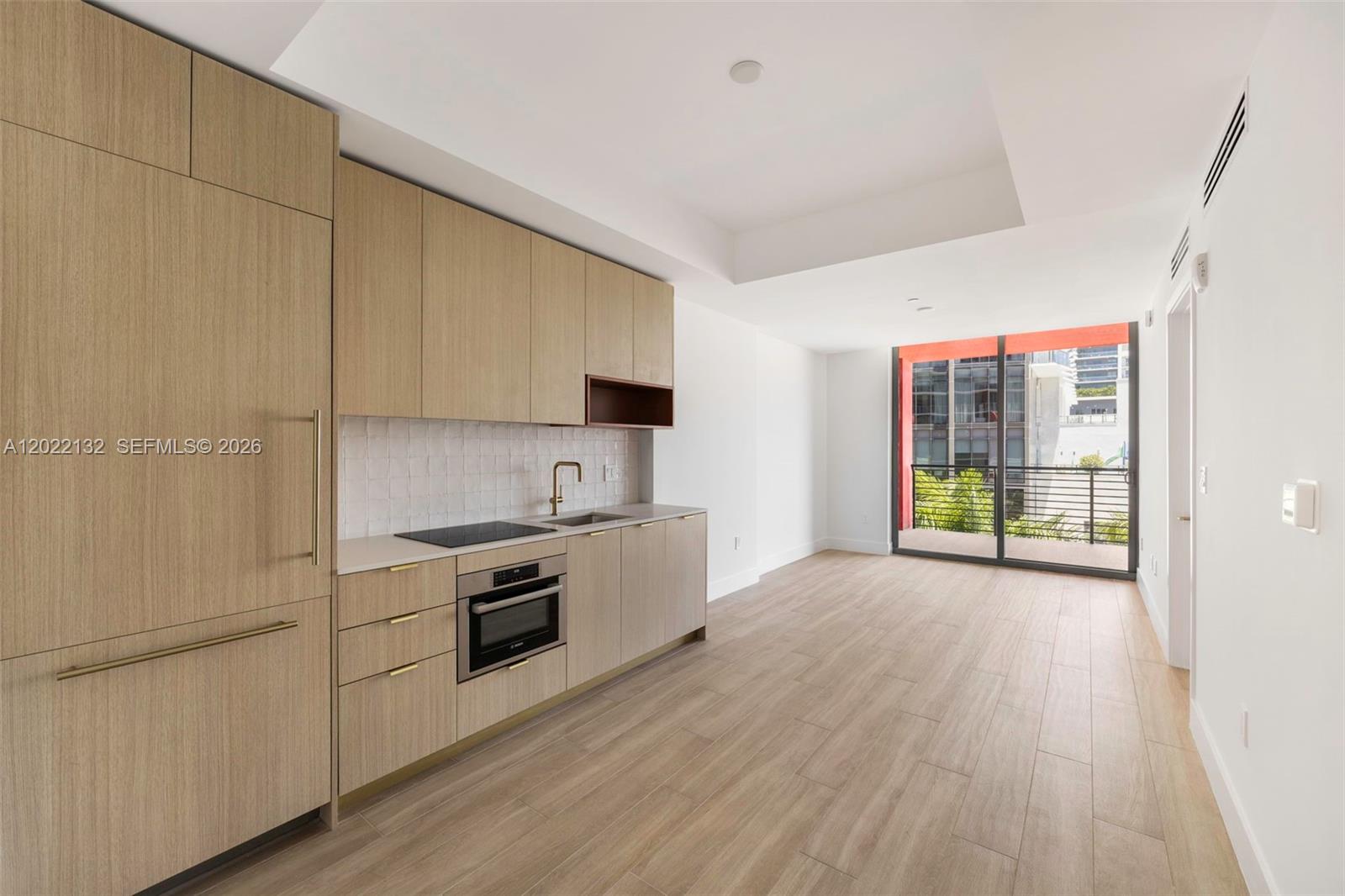 A modern kitchen with light wood cabinetry and a balcony view in an open-plan room — 90 NE 32nd St # 504, Miami FL 33127, MIAMI, FL
