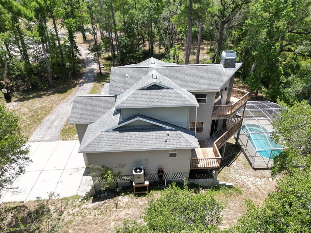 An aerial view of a two-story house with a screened pool and wooded surroundings — 3451 MCKETHAN ROAD, DADE CITY, FL