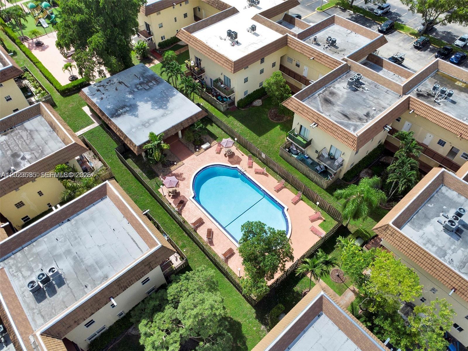 An aerial view shows a swimming pool surrounded by apartment buildings and green lawns — 8550 SW 109th Ave # 119, Miami FL 33173, MIAMI, FL