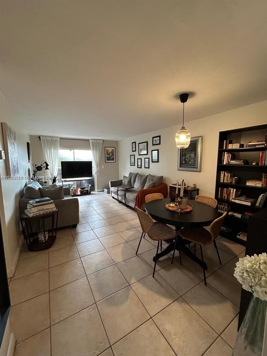 This living and dining area features tile flooring, a dark round table, and a bookshelf — 8550 SW 109th Ave # 119, Miami FL 33173, MIAMI, FL
