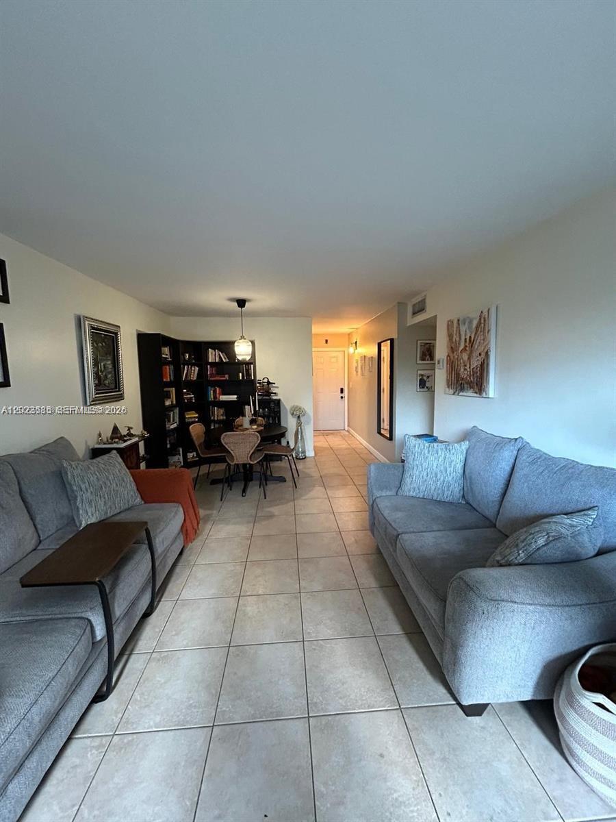 A living room features two gray sofas, a dining area with a bookshelf, and tile flooring — 8550 SW 109th Ave # 119, Miami FL 33173, MIAMI, FL