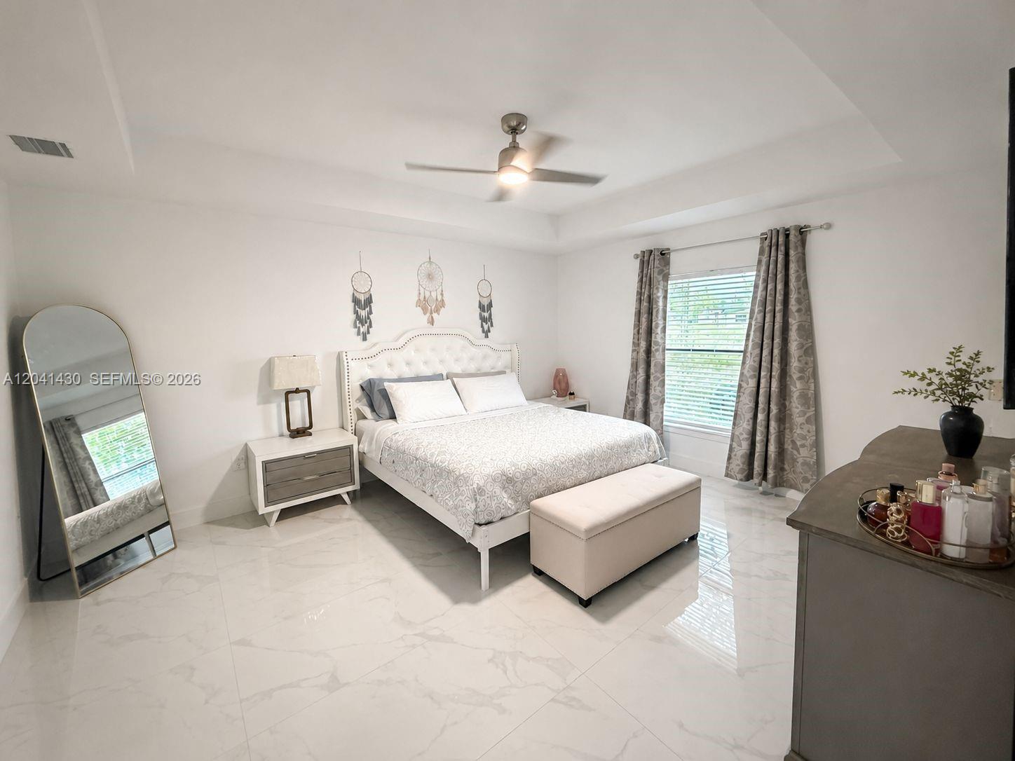 A bedroom features a tufted headboard, a floor mirror, and tile flooring — 1006 Rush Ave, Lehigh Acres FL 33972, LEHIGH ACRES, FL