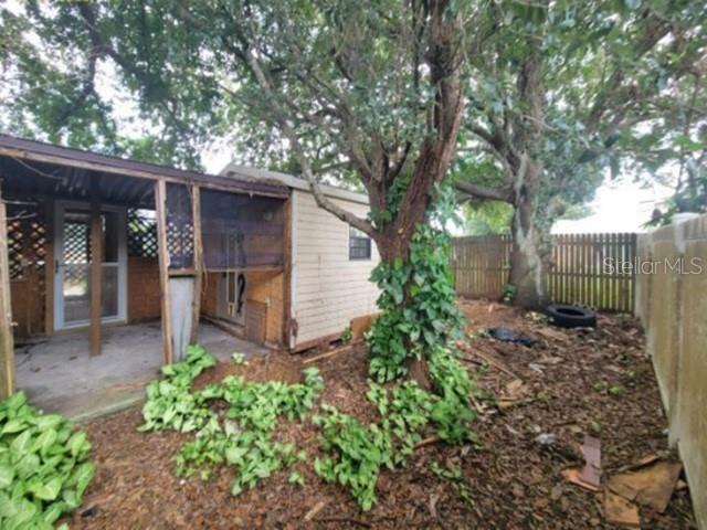 A small, weathered shed with a screened-in porch stands in a yard with large trees — 713 TOULON DRIVE, KISSIMMEE, FL
