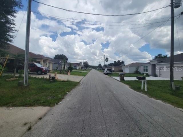 A residential street view showing houses, parked cars, and utility poles under a cloudy sky — 713 TOULON DRIVE, KISSIMMEE, FL