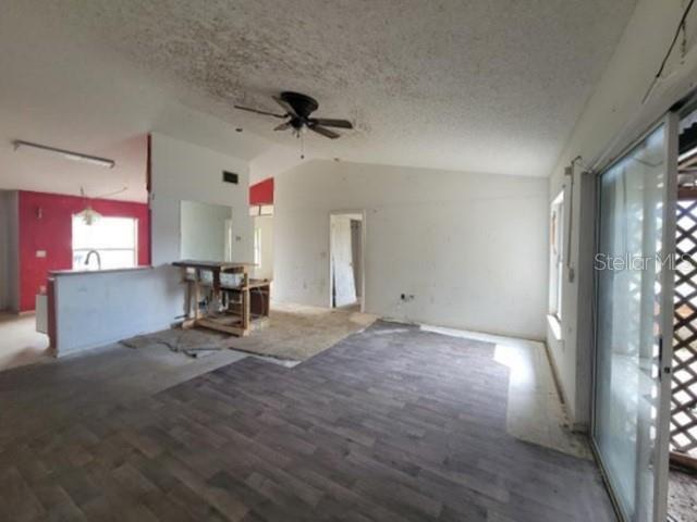 An open-concept living area features a ceiling fan, wood-look flooring, and a kitchen island — 713 TOULON DRIVE, KISSIMMEE, FL