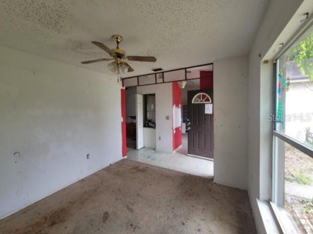 An interior view of a room with a ceiling fan, carpeted floor, and an entryway — 713 TOULON DRIVE, KISSIMMEE, FL