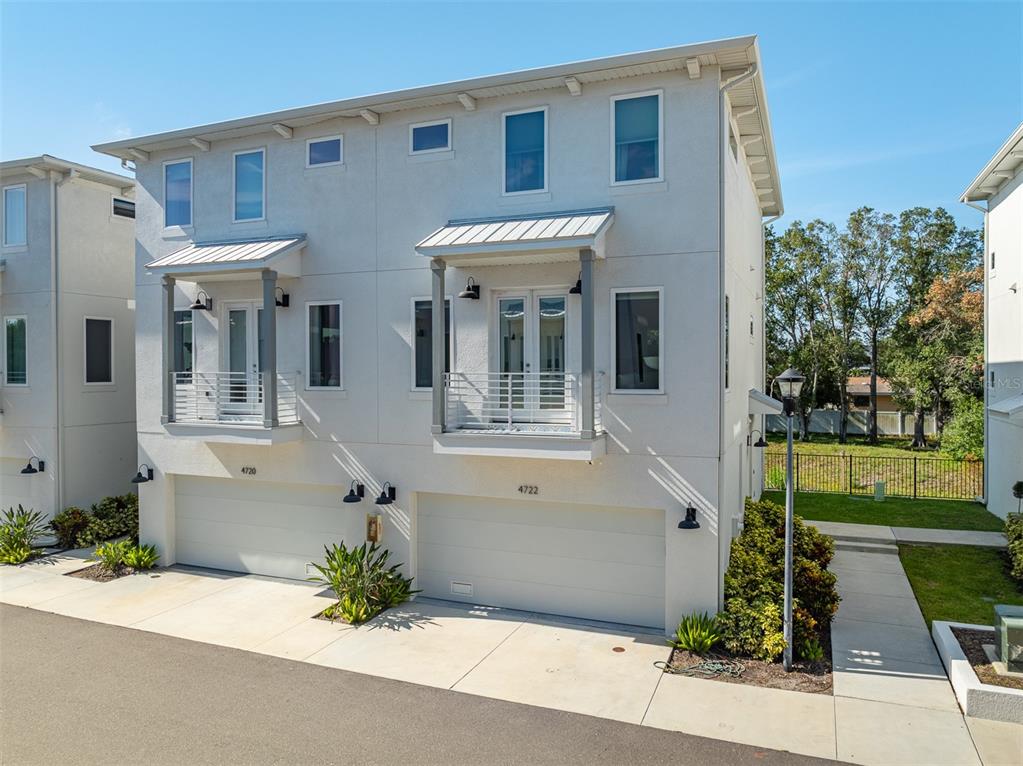 Exterior view of a two-story duplex with white stucco walls, balconies, and two garage doors — 4722 LEGACY PARK DRIVE, TAMPA, FL