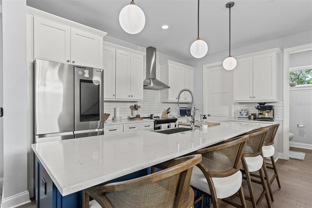 A modern kitchen features white cabinetry, a large quartz island, and blue base cabinets — 4722 LEGACY PARK DRIVE, TAMPA, FL