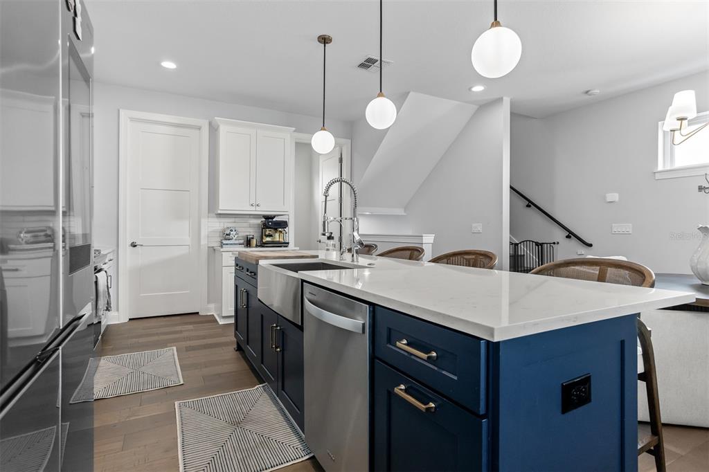 A kitchen features a blue island with a farmhouse sink, white countertops, and pendant lighting — 4722 LEGACY PARK DRIVE, TAMPA, FL