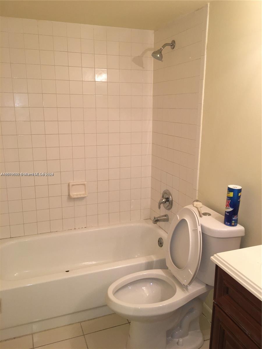 A bathroom features a white tiled shower-tub combination next to a white toilet — 3396 Foxcroft Rd # 308, Miramar FL 33025, MIRAMAR, FL