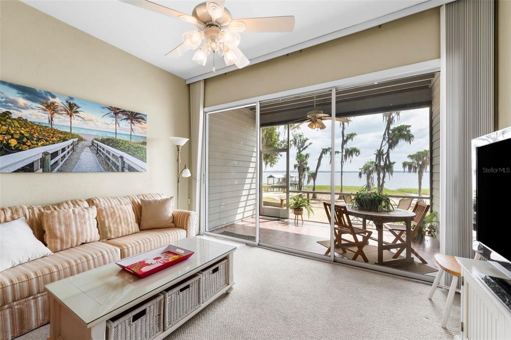 A living room with a striped sofa, glass coffee table, and sliding doors to a patio — 21134 NE 101ST AVENUE, EARLETON, FL