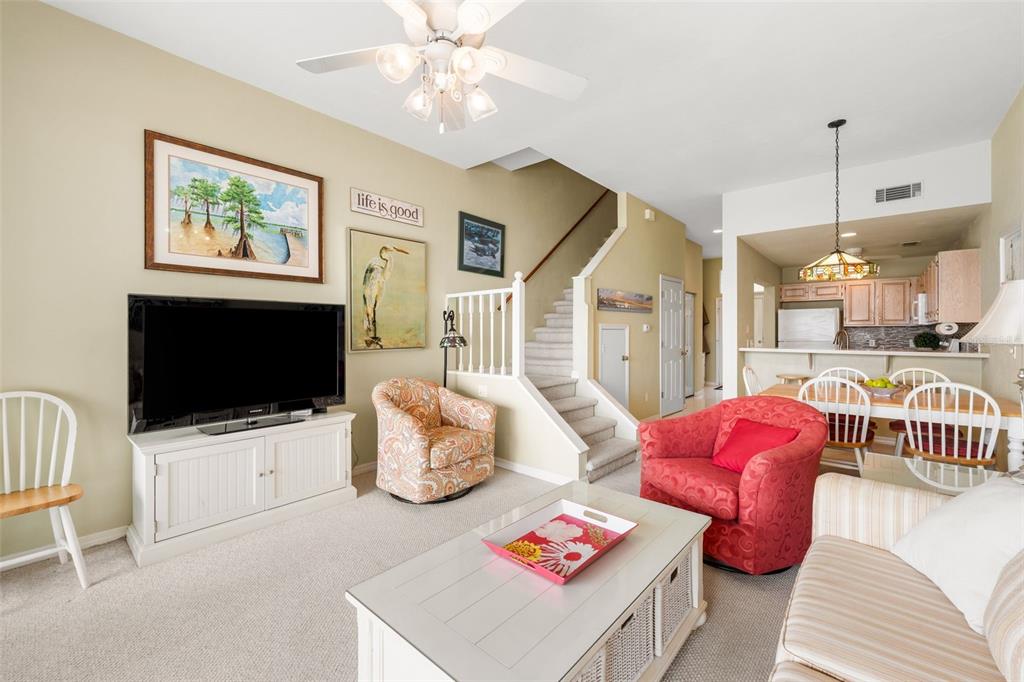 A living room features a television, stairs, a red armchair, and an adjacent kitchen area — 21134 NE 101ST AVENUE, EARLETON, FL