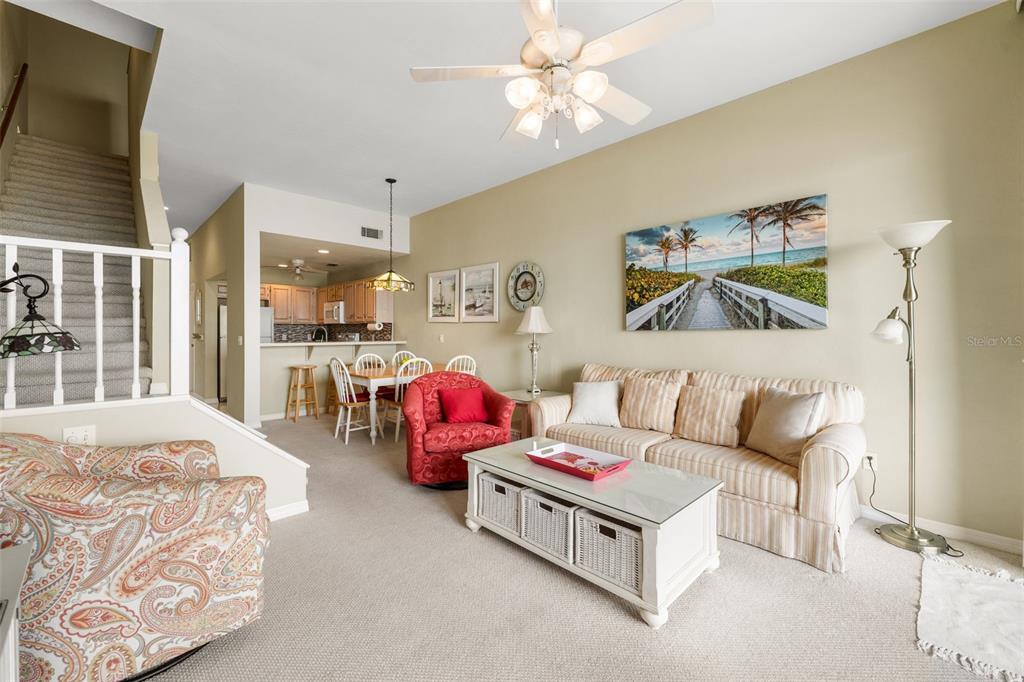 A living room with a beige sofa, patterned armchair, and an open kitchen in the background — 21134 NE 101ST AVENUE, EARLETON, FL