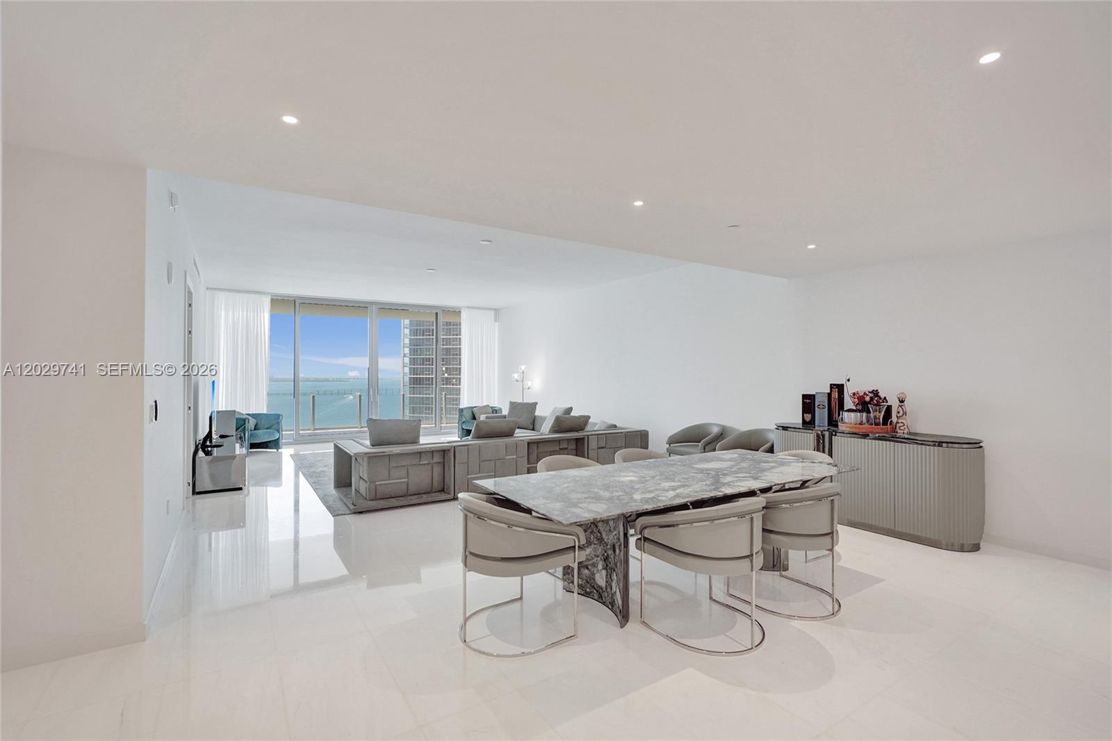 A modern open-plan living and dining area features white tile floors and ocean views — 300 Biscayne Boulevard Way # 3304C, Miami FL 33131, MIAMI, FL