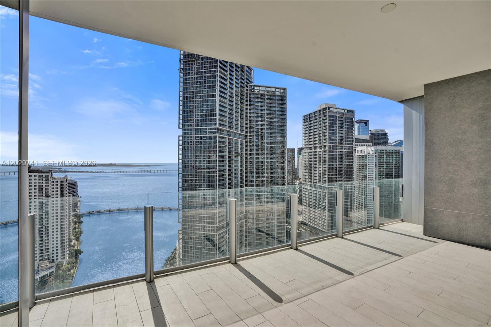A balcony with glass railings overlooks a bay and city skyline — 300 Biscayne Boulevard Way # 3304C, Miami FL 33131, MIAMI, FL