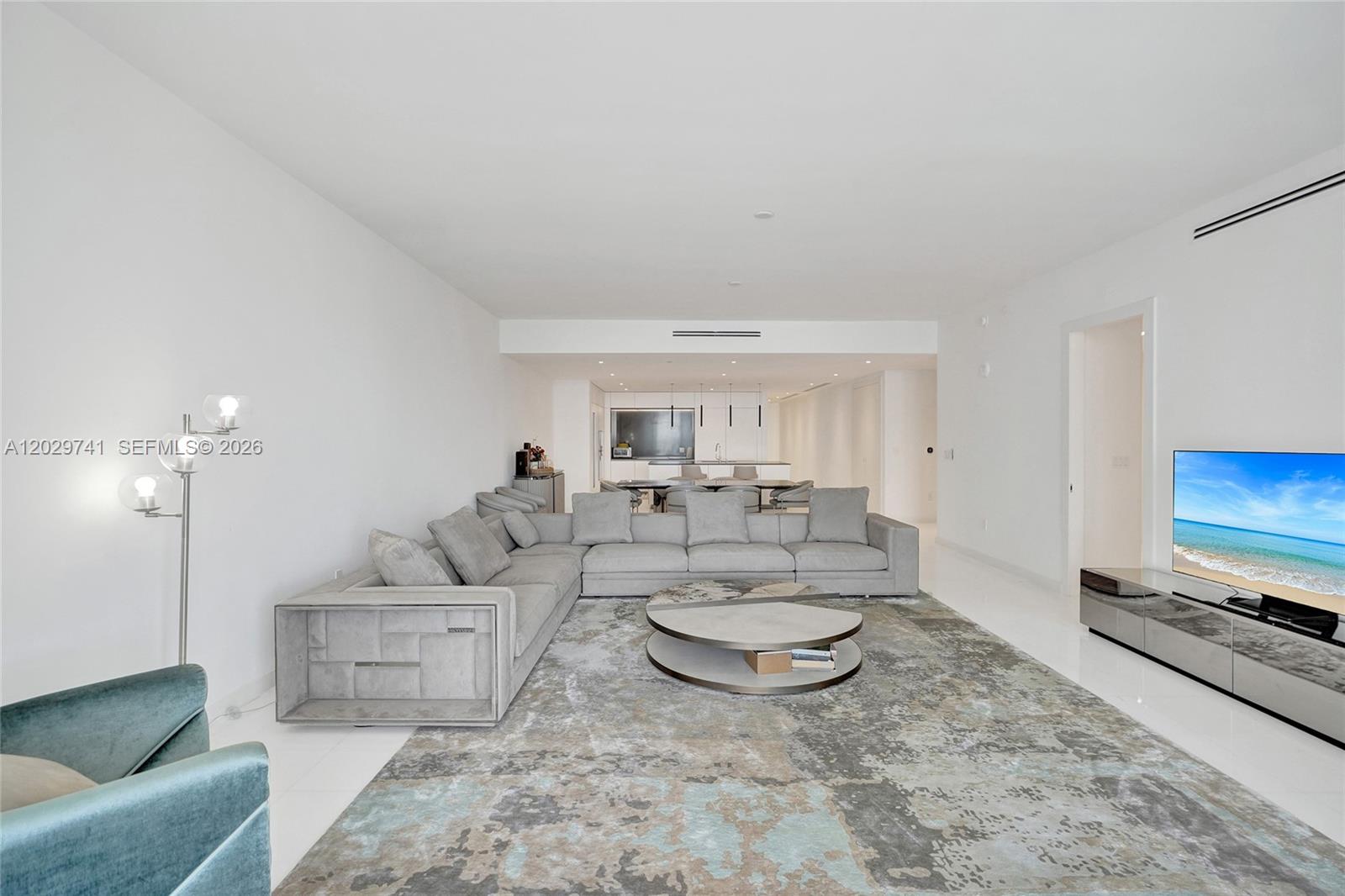 A modern living room features a large gray sectional, a round coffee table, and a television — 300 Biscayne Boulevard Way # 3304C, Miami FL 33131, MIAMI, FL