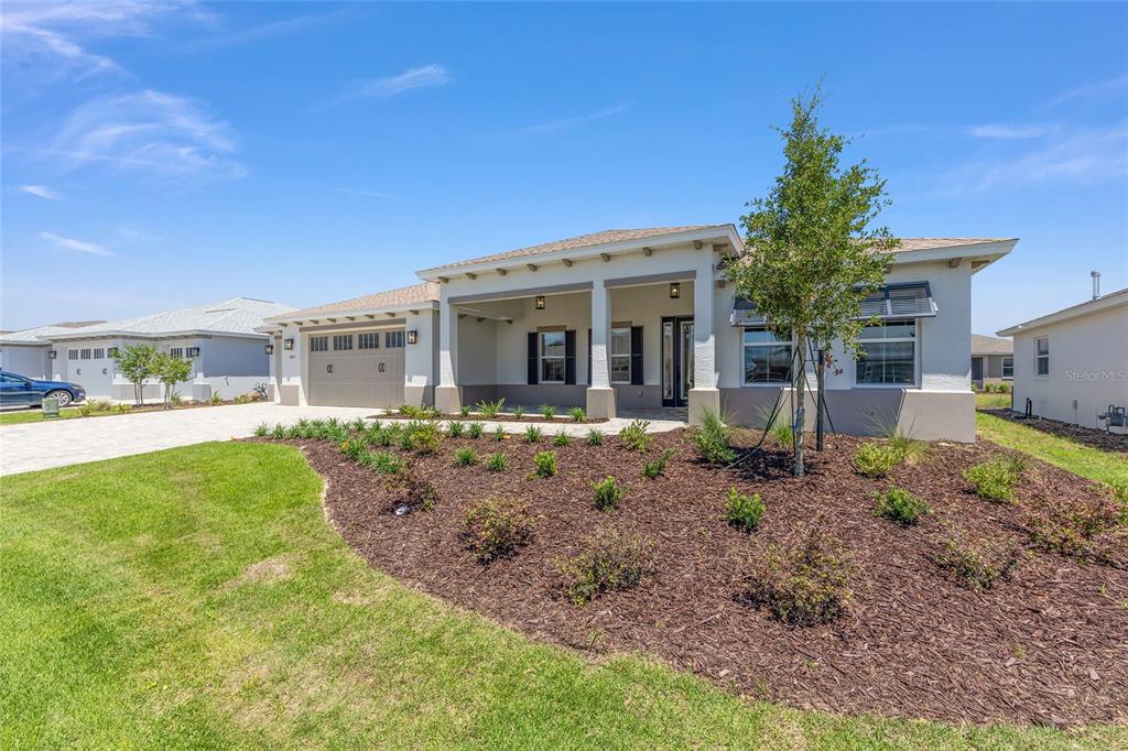 A single-story house with a beige stucco exterior, a covered front porch, and a garage — 10211 SW 82ND PL ROAD, OCALA, FL
