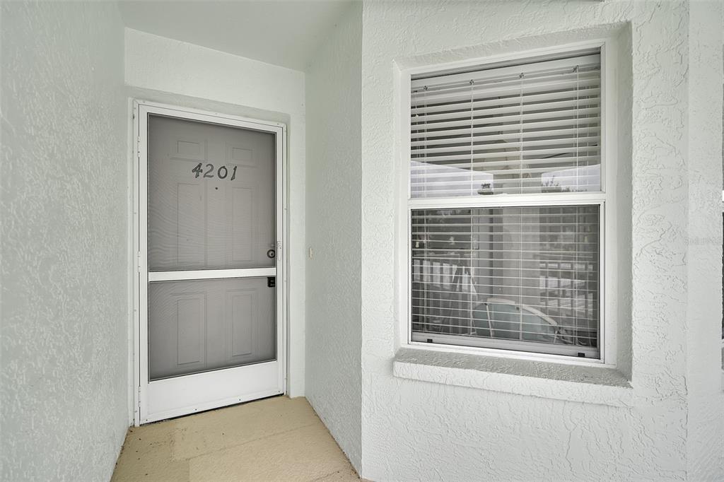 A white front door with a screen and a window with blinds on a porch — 5725 GREENWOOD AVENUE UNIT 4201, NORTH PORT, FL