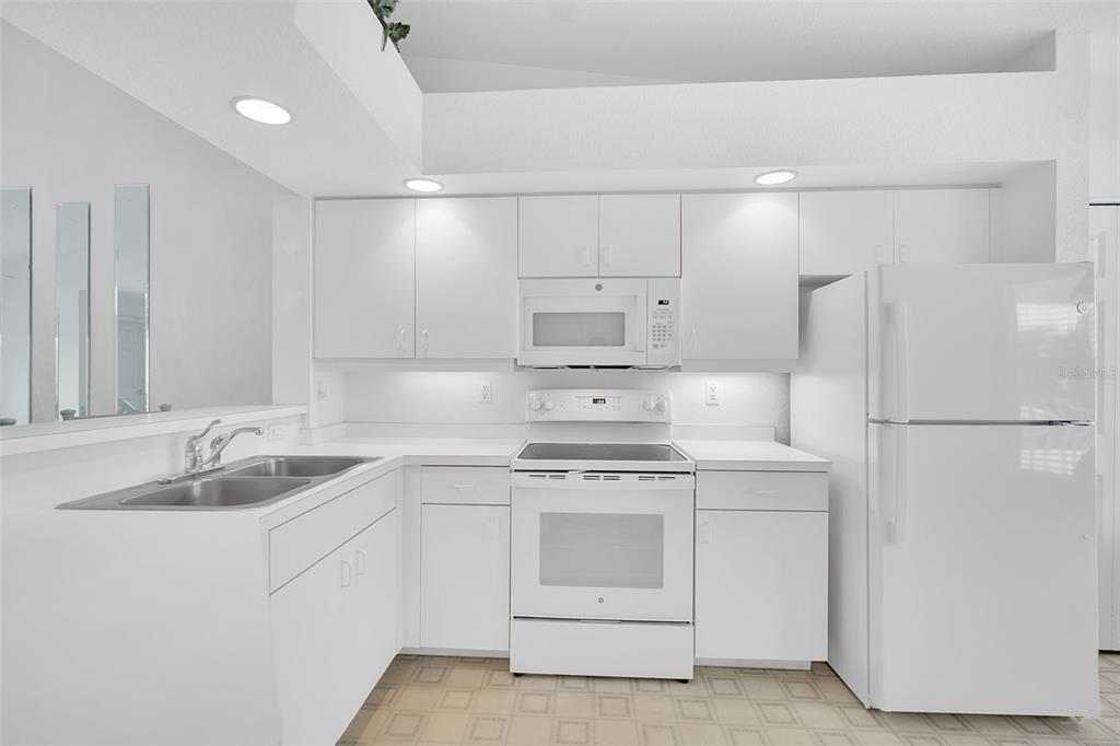 A bright kitchen features white cabinets, white appliances, and a double-basin sink — 5725 GREENWOOD AVENUE UNIT 4201, NORTH PORT, FL