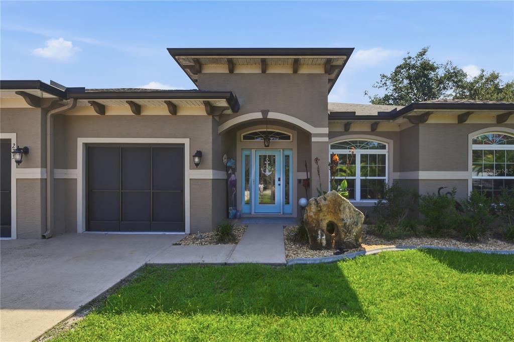 A single-story house with a brown stucco exterior, a blue front door, and a garage — 225 BIRCHWOOD DRIVE, PALM COAST, FL