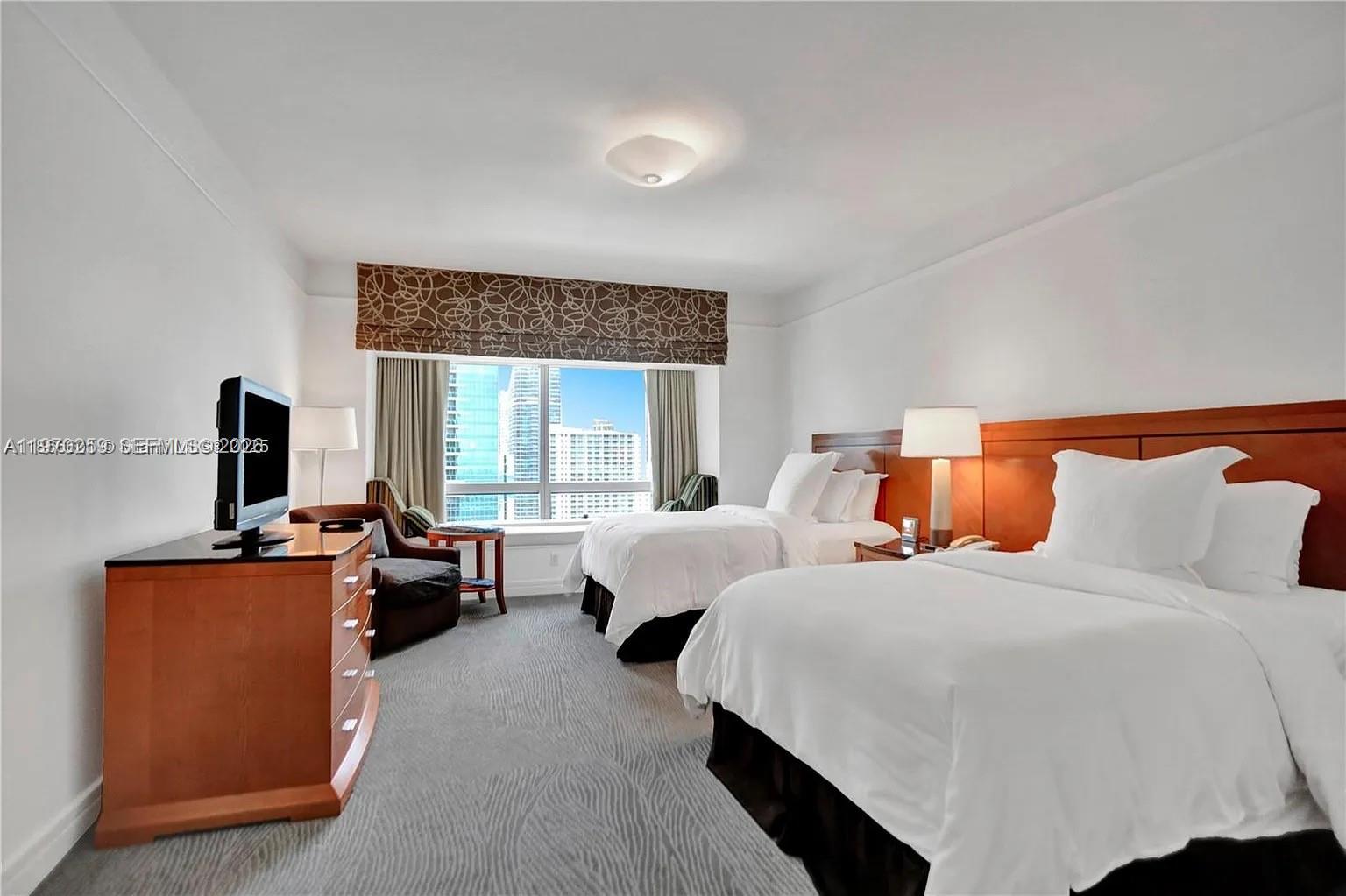 A hotel room features two beds, a wooden dresser with a television, and city views — 1435 Brickell Ave # 3212, Miami FL 33131, MIAMI, FL