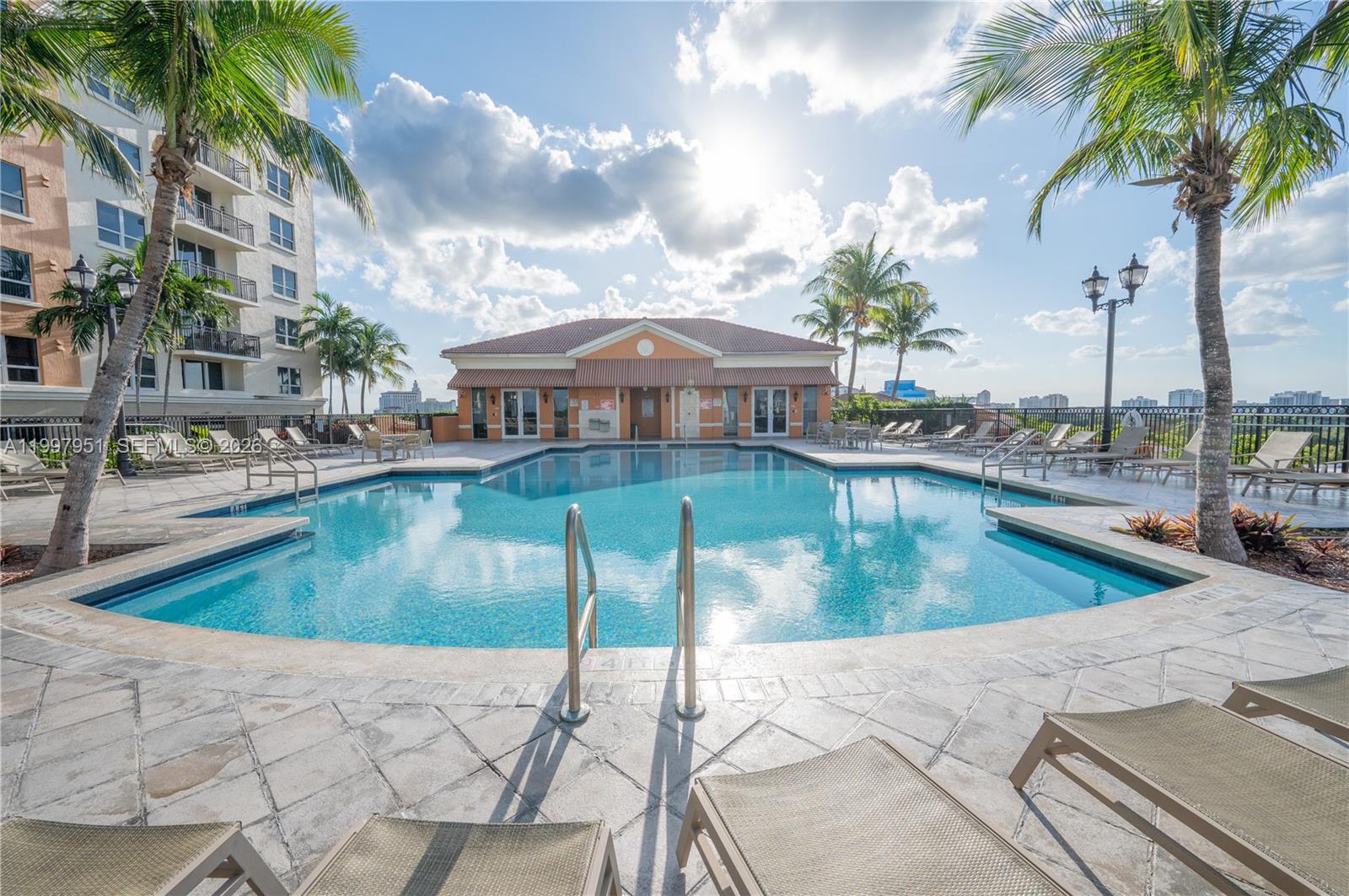 A swimming pool with lounge chairs and palm trees sits in front of a building — 3232 SW 22nd Ter # 607, Miami FL 33145, MIAMI, FL