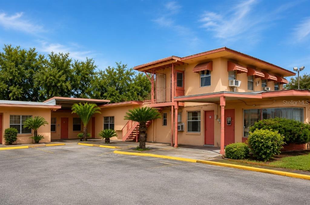 A two-story peach-colored motel building features an exterior staircase and a paved parking lot — 1306 S 14TH STREET, LEESBURG, FL