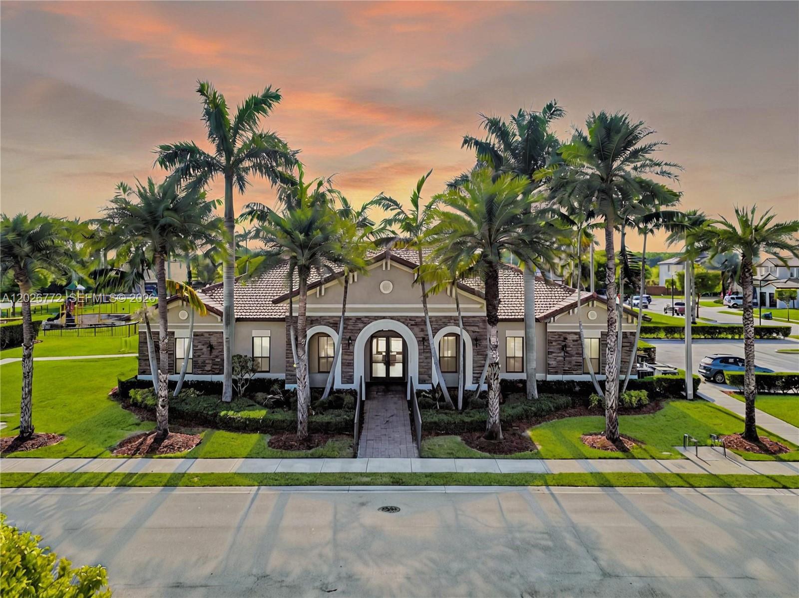 An exterior view of a single-story community clubhouse with palm trees and a paved walkway — 11866 SW 152nd Pl, Miami FL 33196, MIAMI, FL