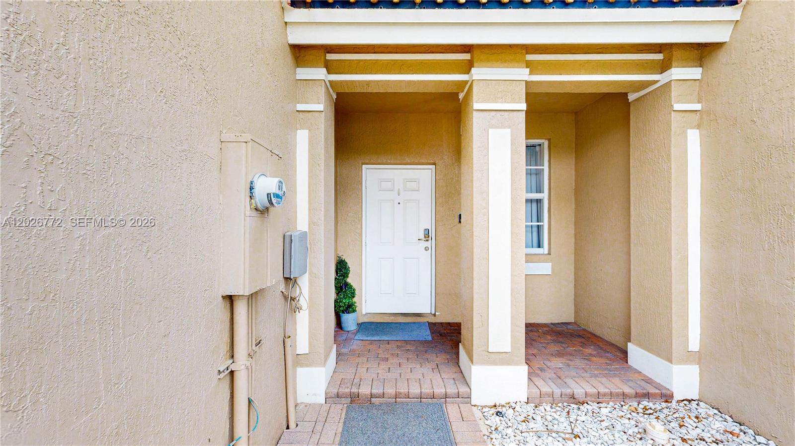 The exterior entrance features a white door, brick flooring, and a tan stucco facade — 11866 SW 152nd Pl, Miami FL 33196, MIAMI, FL