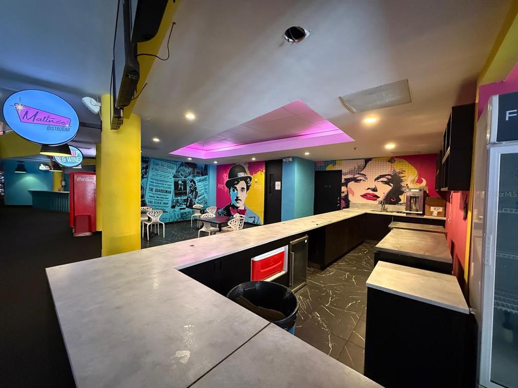 A bar area features a concrete countertop, black cabinetry, and walls decorated with celebrity murals — 86 CALLE REINA ST, PONCE, PR