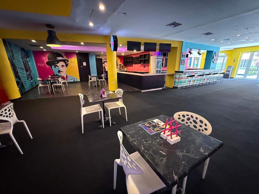 A colorful lounge area features tables, chairs, a bar, and a Charlie Chaplin wall mural — 86 CALLE REINA ST, PONCE, PR